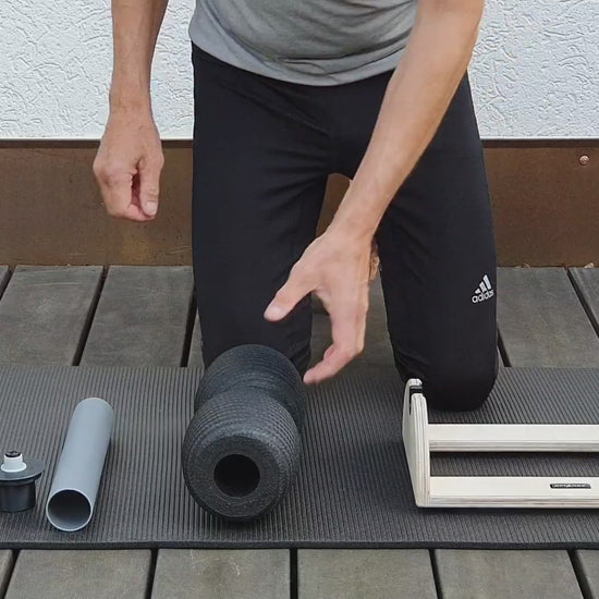 Video-Anleitung zur Erstmontage: Ein Nutzer führt das DRYANGL Innenrohr werkzeuglos in den Kern einer Blackroll Faszienrolle ein, setzt die seitlichen Adapter auf und spannt die fertige Rolle in die SmartRoller Station ein.