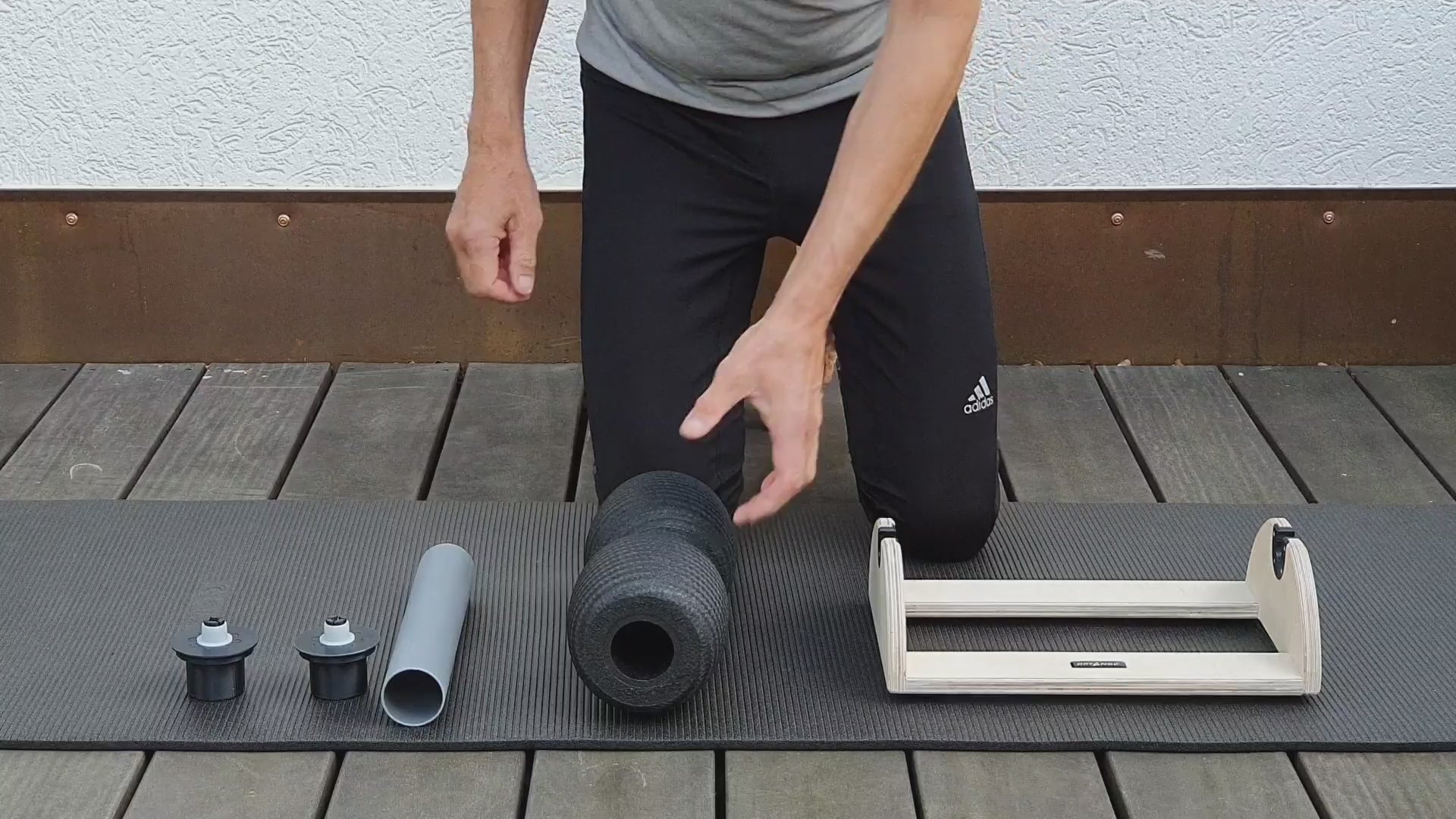 Video-Anleitung zur Erstmontage: Ein Nutzer führt das DRYANGL Innenrohr werkzeuglos in den Kern einer Blackroll Faszienrolle ein, setzt die seitlichen Adapter auf und spannt die fertige Rolle in die SmartRoller Station ein.